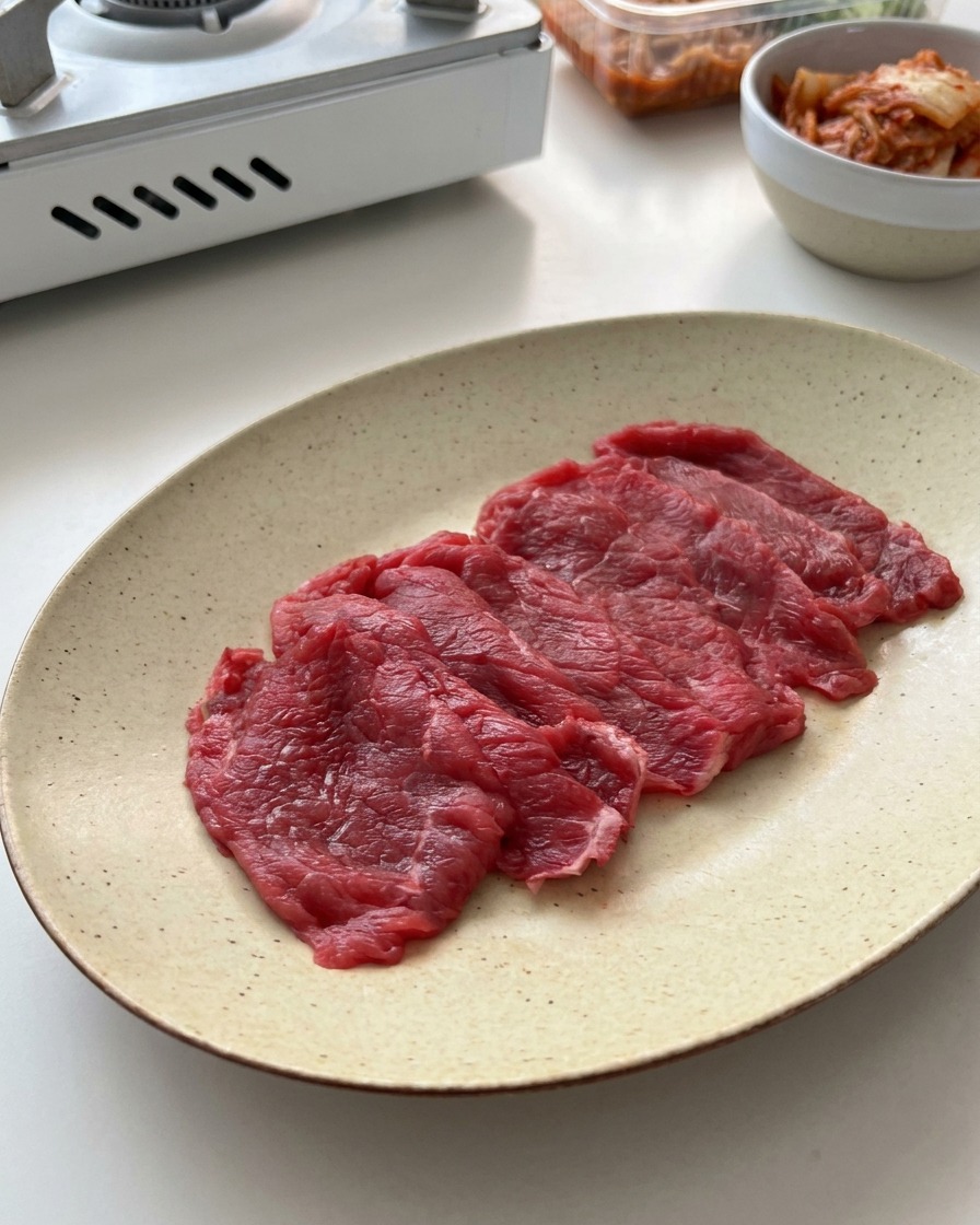 Fettine di manzo crudo disposte su un piatto di ceramica.