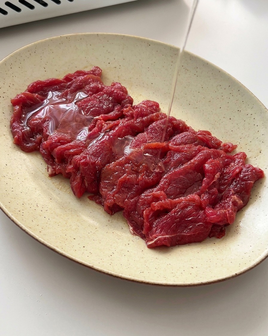 Un filo dolio versato sulle fettine di manzo marinate.