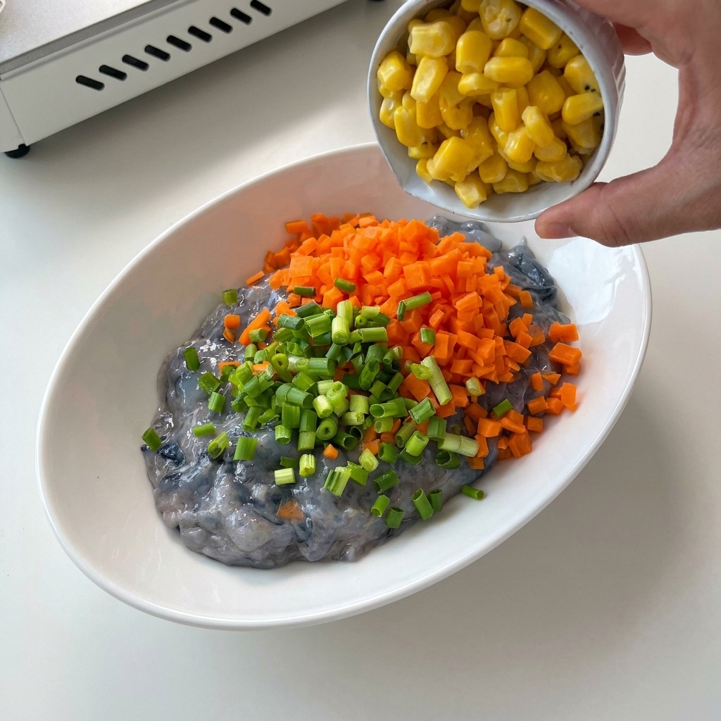 Cipollotto verde tritato versato in una ciotola con pasta di gamberi e carote.