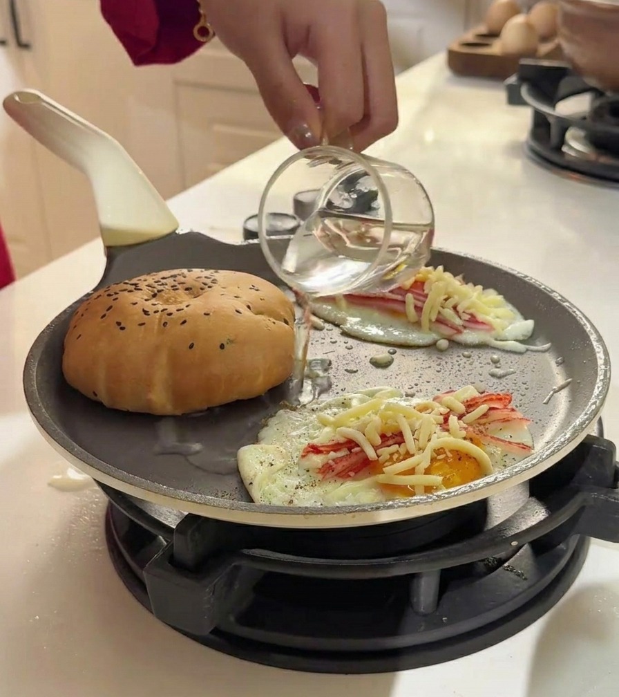 Versare acqua da un bicchiere in padella con uova e panini per creare vapore.