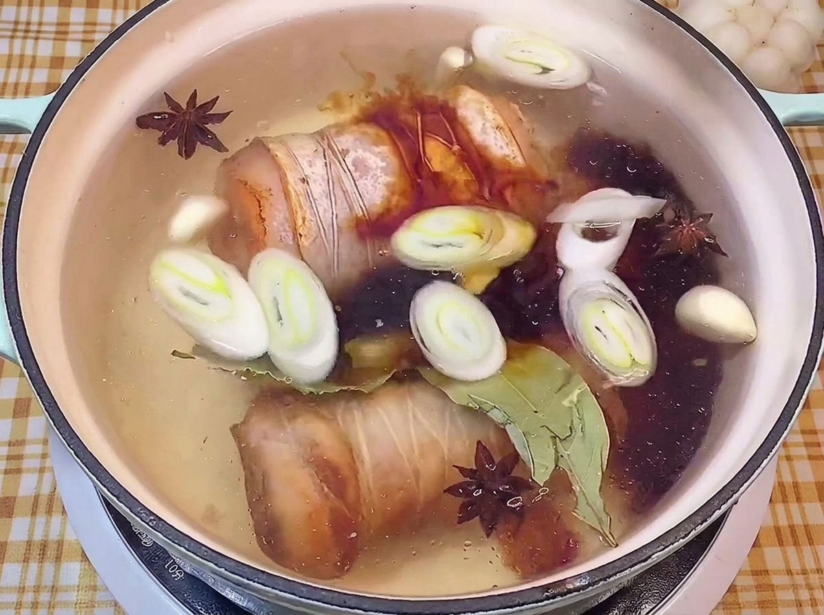 Aggiunta di salsa di soia scura in una pentola con maiale e spezie.