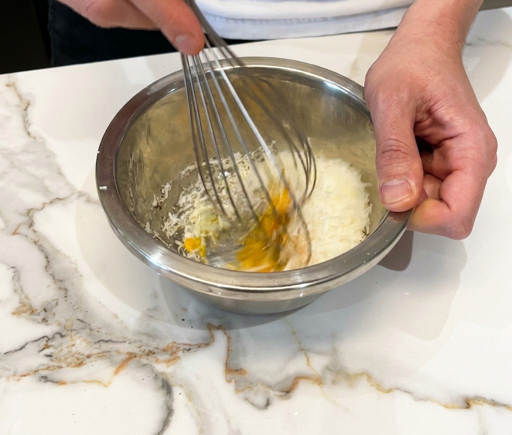 Sbattere uova, formaggio e pepe fino a ottenere una crema densa.