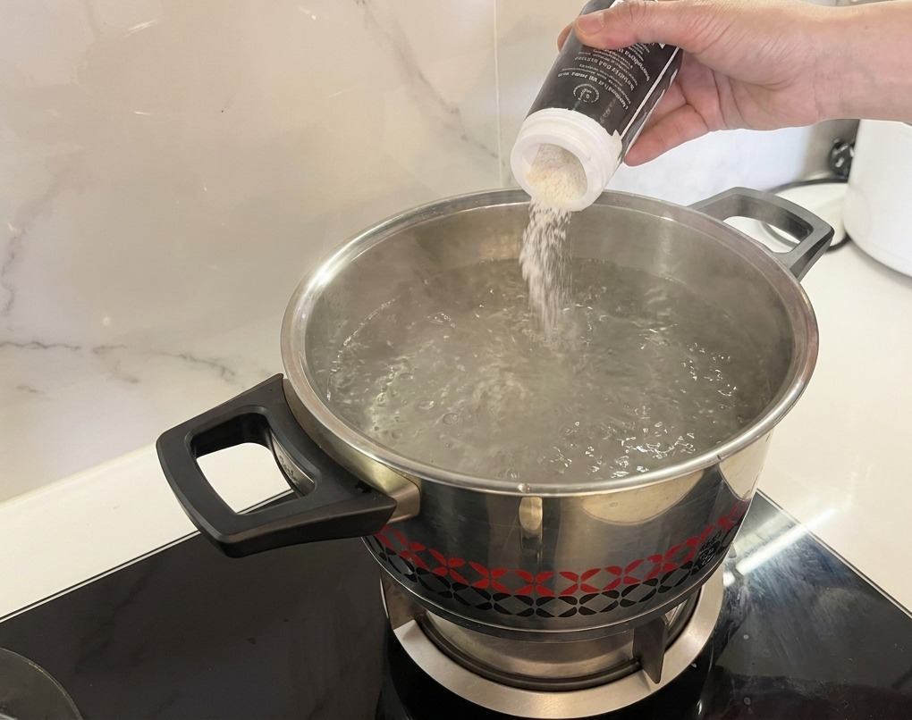 Sale versato in una pentola dacqua che bolle intensamente.