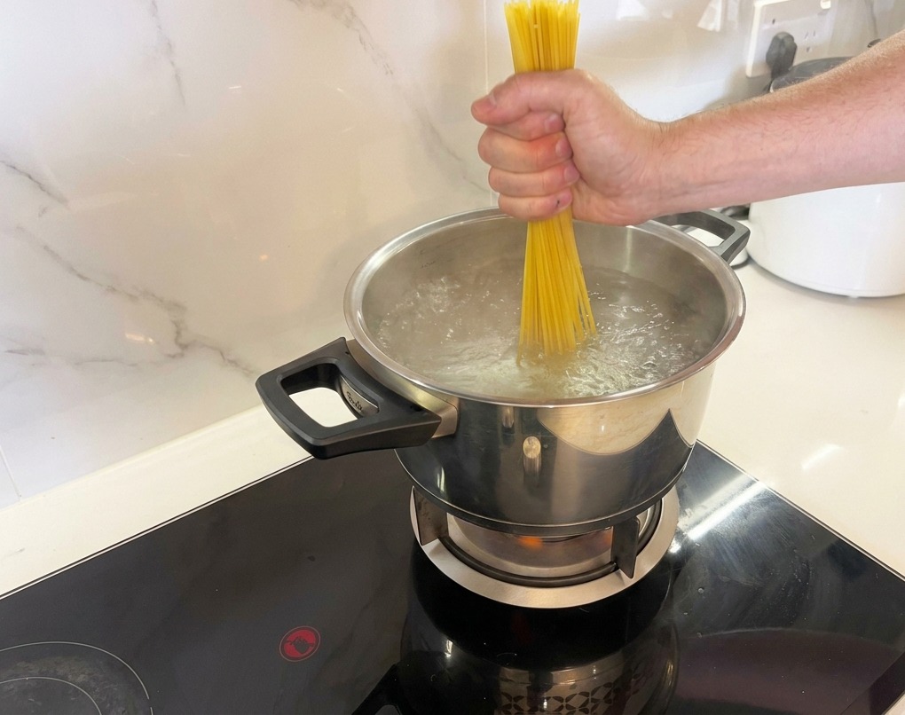 Spaghetti immersi nellacqua bollente salata.