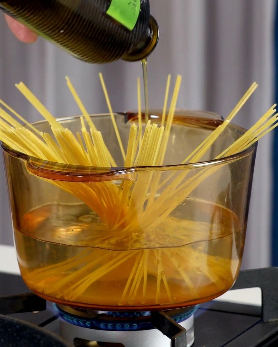 Una mano che sparge sale marino in una pentola trasparente di acqua bollente con spaghetti.