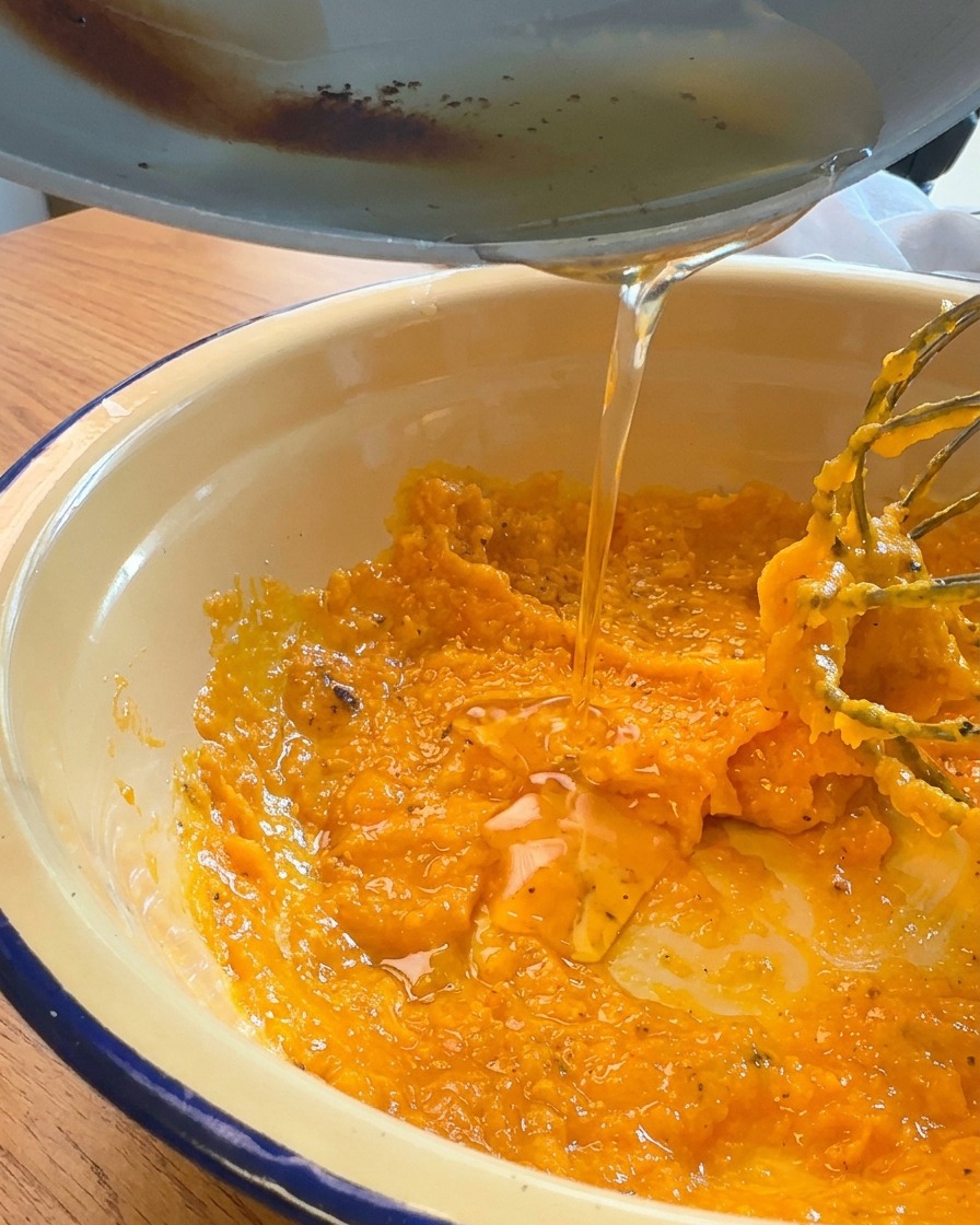 Grasso di maiale fuso versato da una padella in una ciotola con tuorli e formaggio.