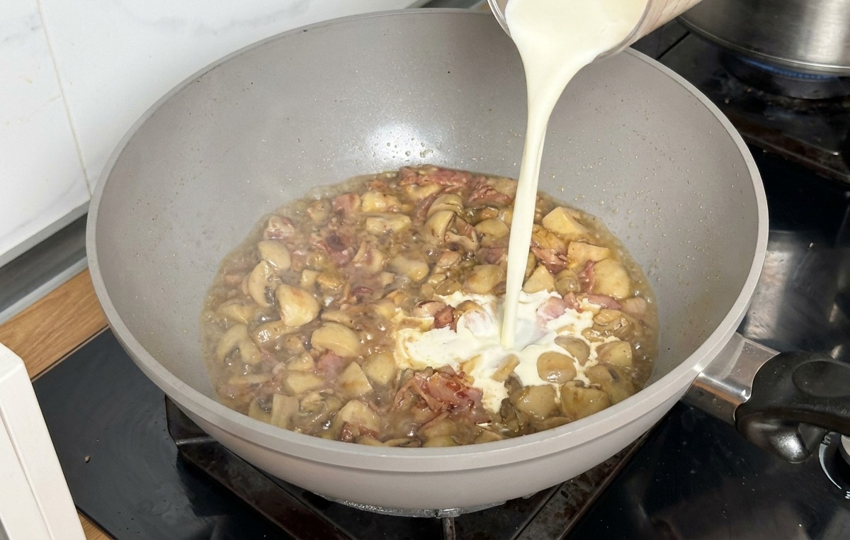 Panna da cucina versata da un misuratore in una padella con brodo ridotto e funghi.