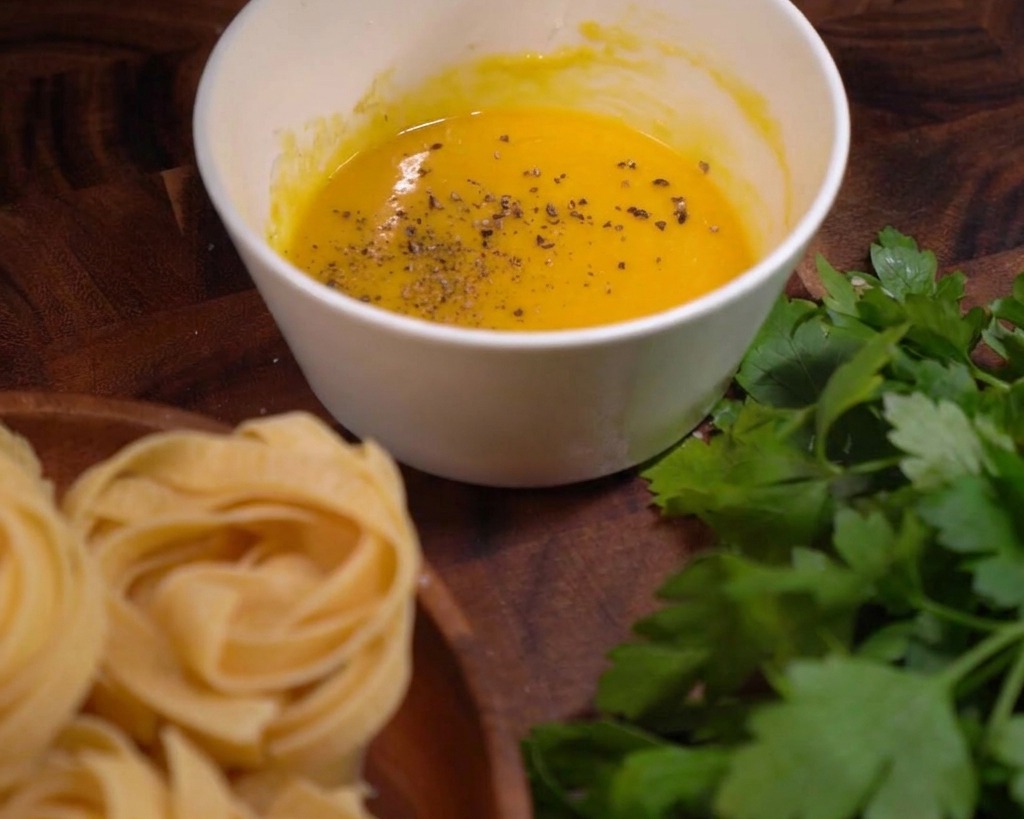 Fiocchi di pepe nero macinato grossolanamente sopra la crema di uova e formaggio.