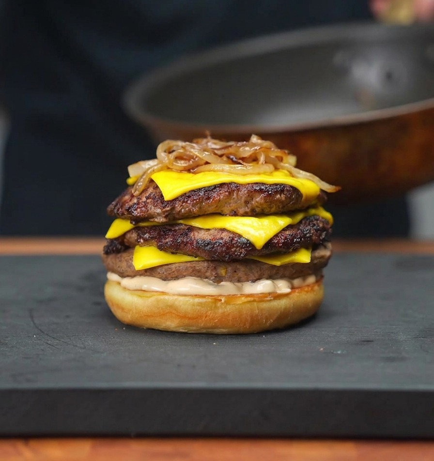 Cipolle caramellate che vengono adagiate sopra i patty di carne sul panino usando delle bacchette.