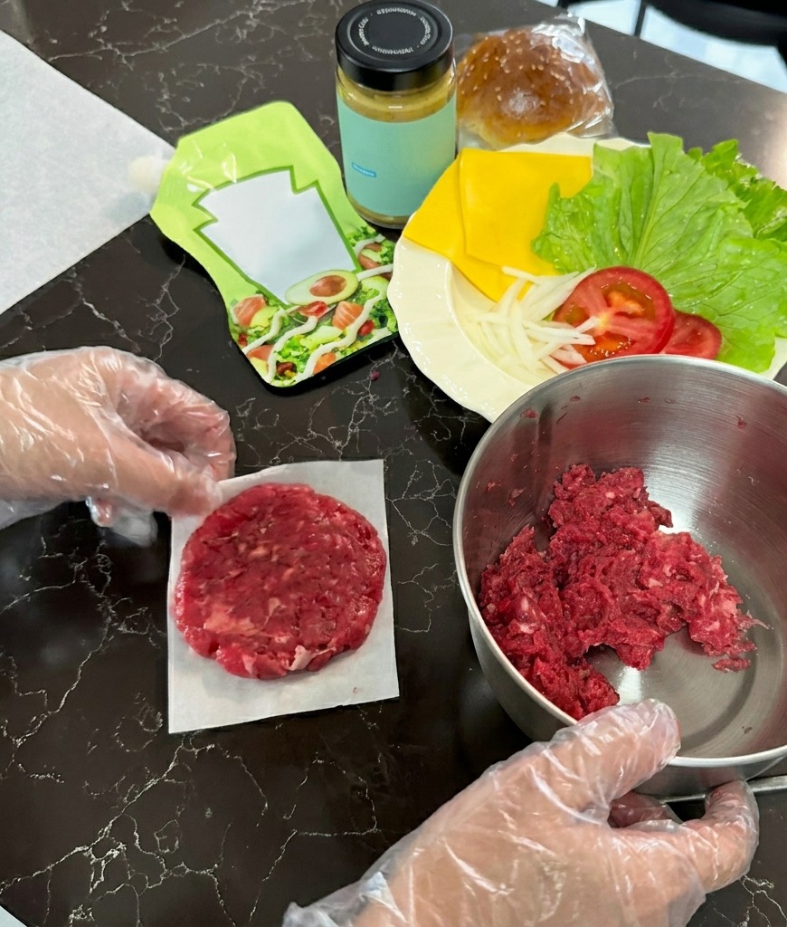 Un hamburger di carne cruda schiacciato in un cerchio sottile su un quadrato di carta forno.
