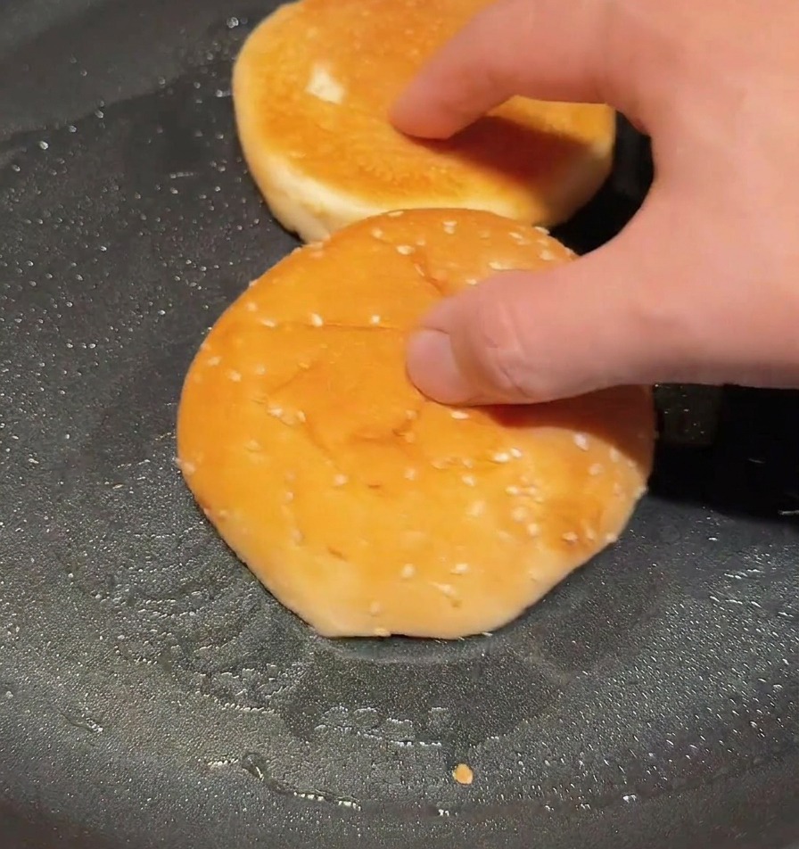 Metà di pane per hamburger tostate in una padella asciutta finché la superficie non è dorata.