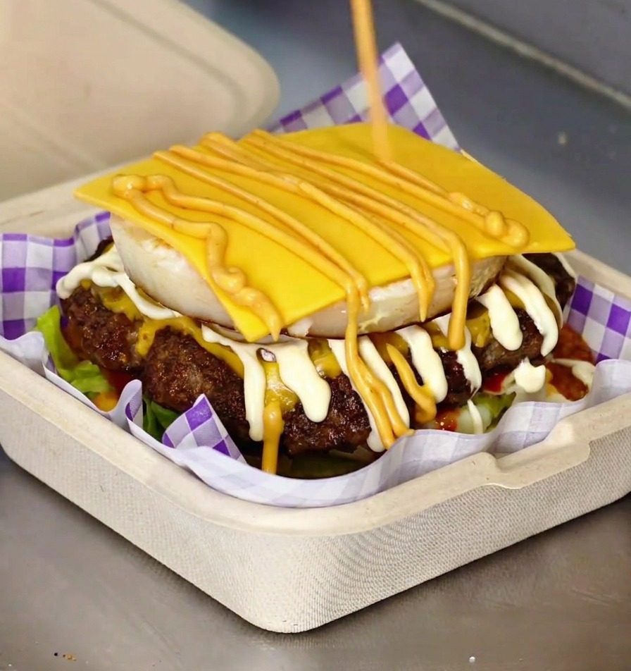 Un burger gourmet completo con uovo fritto e formaggio fuso tra i due pezzi di pan brioche tostato.