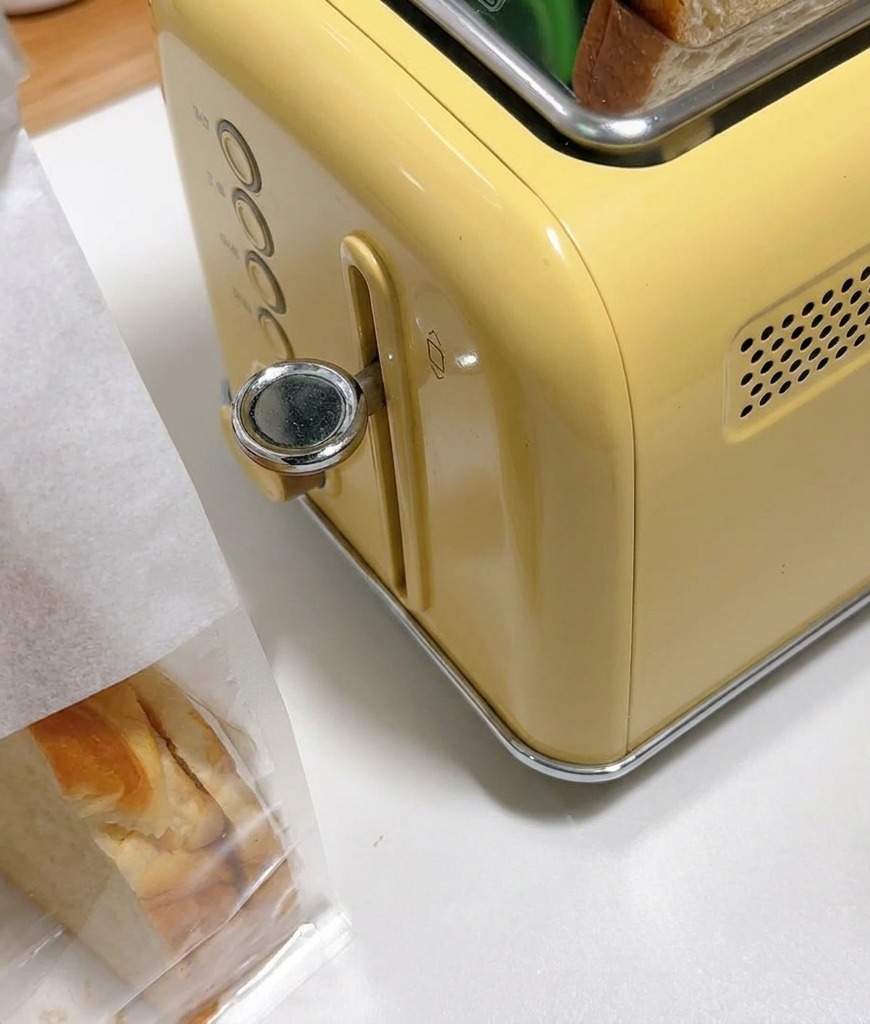 Fette spesse di pane bianco inserite nelle fessure di un tostapane giallo stile vintage.