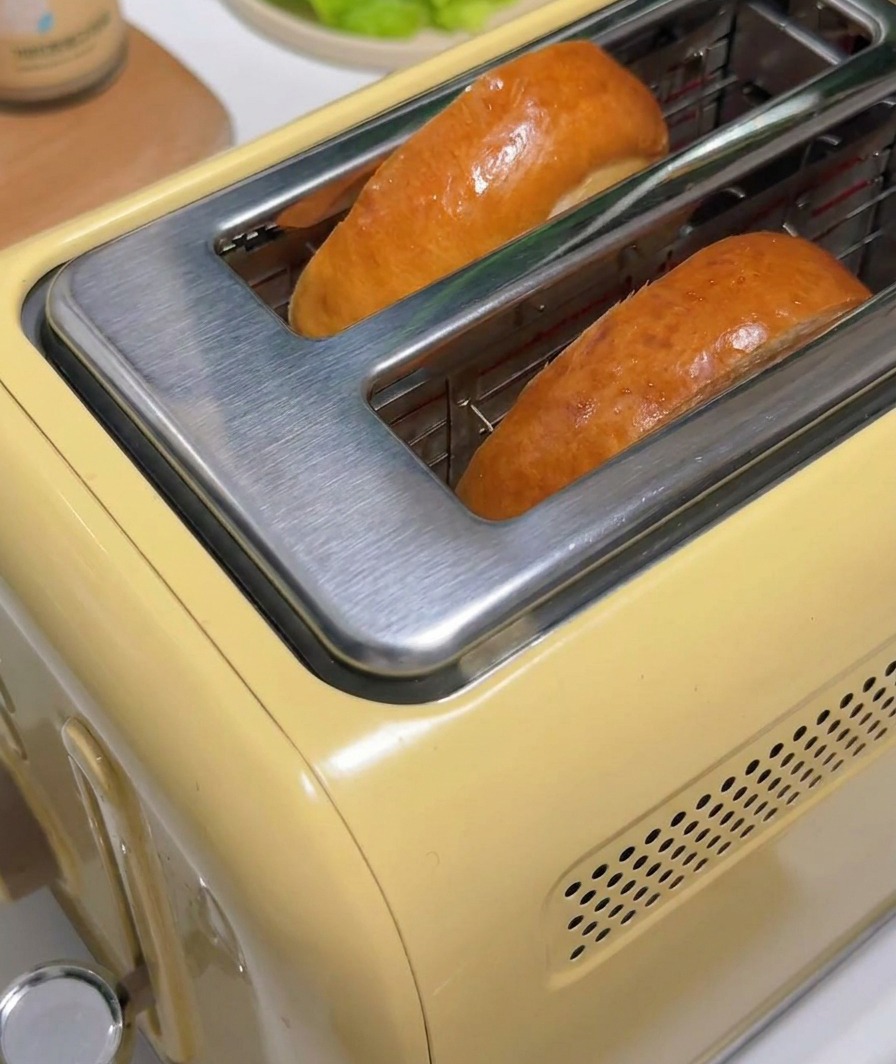 Due fette di pane dorato che escono da un tostapane giallo stile vintage.