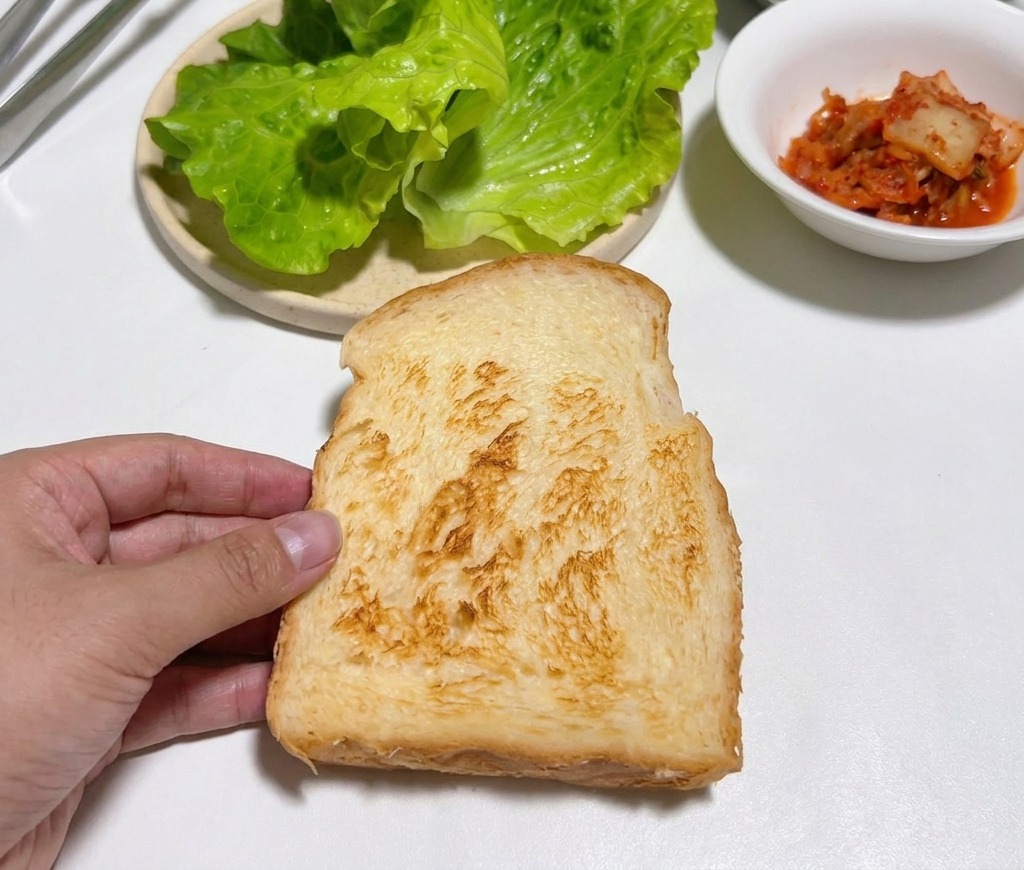 Una mano che tiene una fetta di pane dorato su un tavolo bianco.