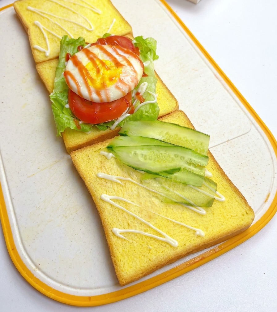 Sottili fette di cetriolo fresco disposte in diagonale su una fetta di pane al latte giallo.