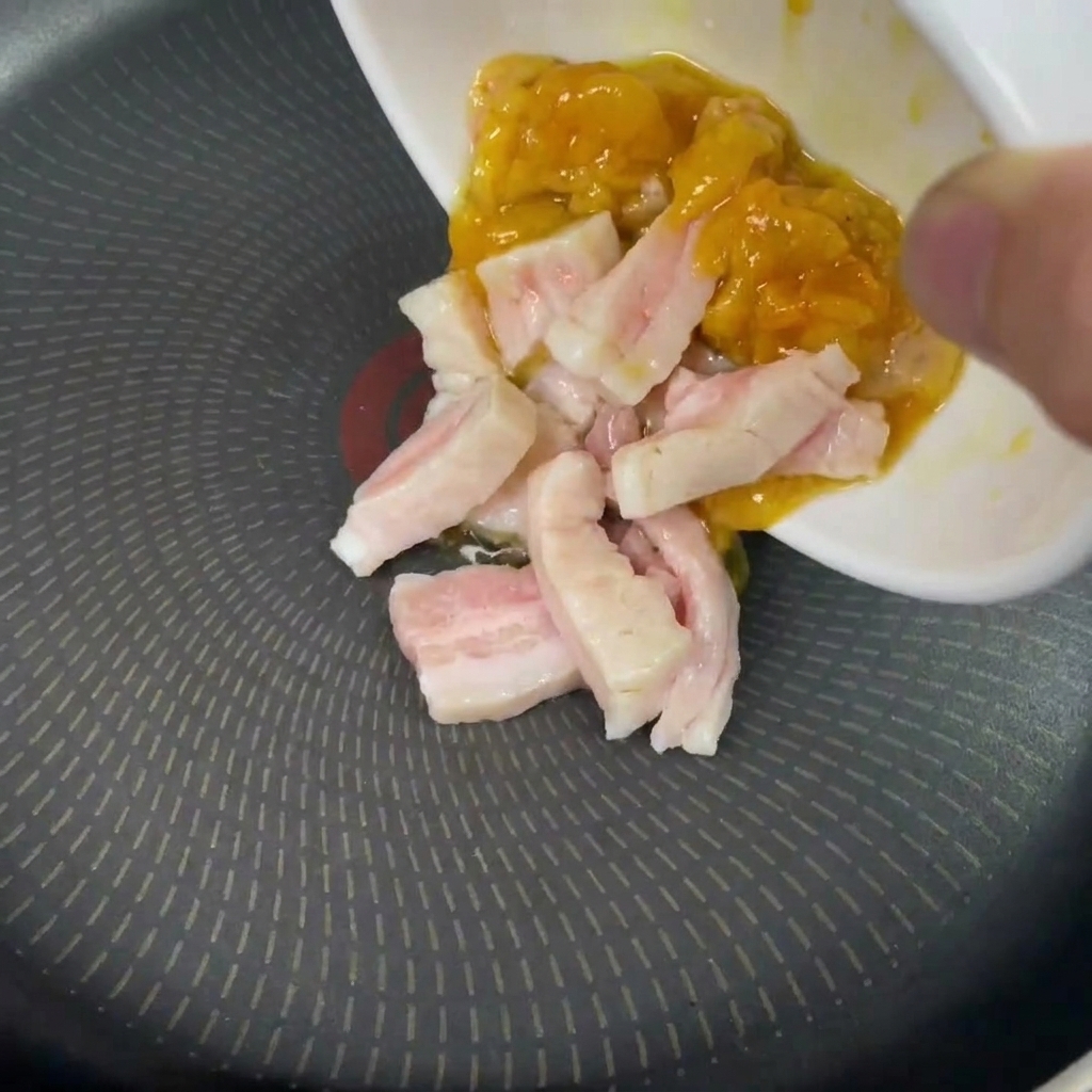 Mano che versa grasso di pollo e maiale in una padella fredda e asciutta.