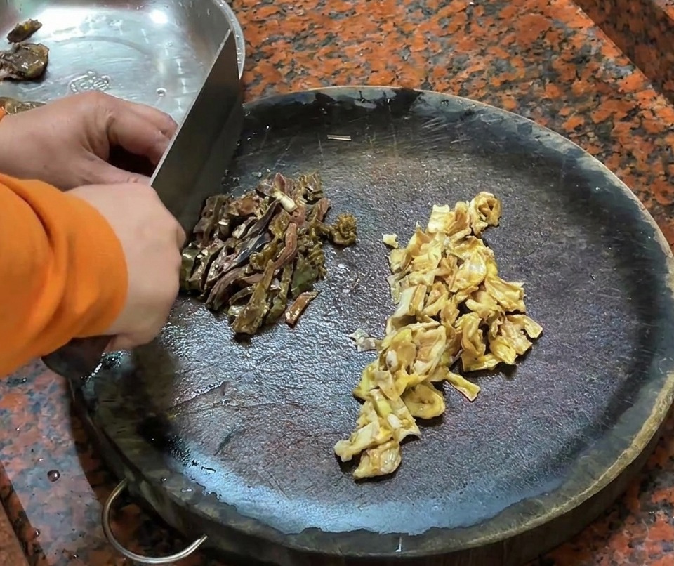 Pezzi di salsiccia di fegato danatra e pelle danatra tagliati su un tagliere di legno.