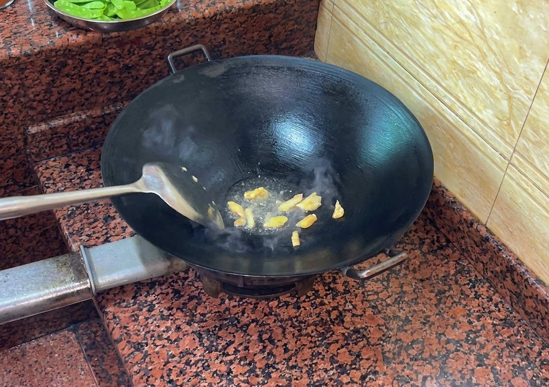 Pezzi di pelle danatra che friggono in un wok caldo, rilasciando grasso liquido.