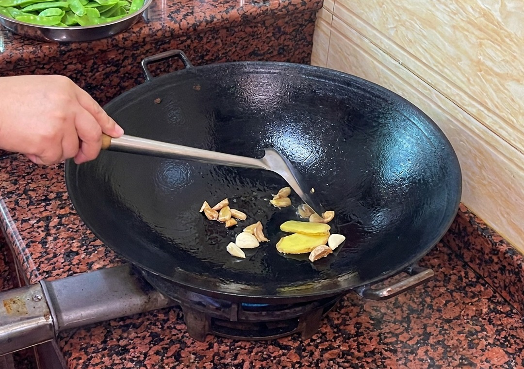 Fettine di zenzero e aglio che soffriggono nel grasso danatra sciolto nel wok.
