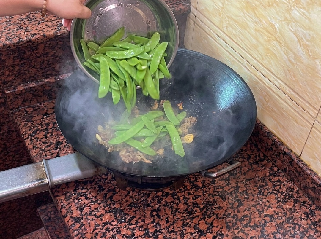 Taccole fresche aggiunte nel wok insieme alla salsiccia e agli aromi.