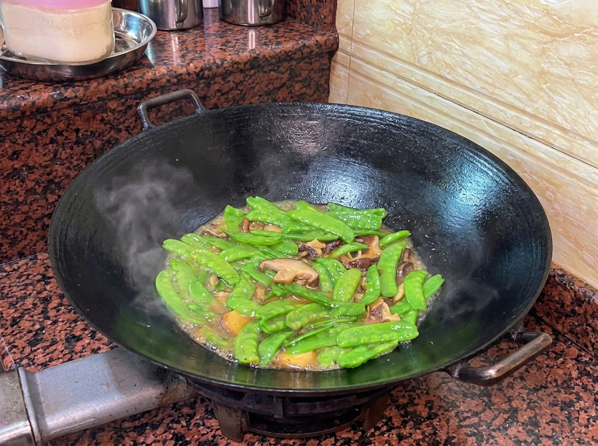 Taccole e salsiccia che insaporiscono nel wok con un fondo di cottura leggero.