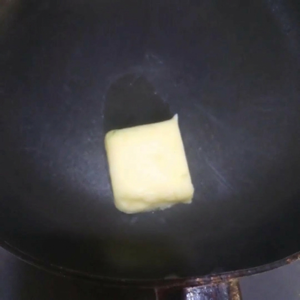 Burro giallo che si scioglie sfrigolando in una padella calda.