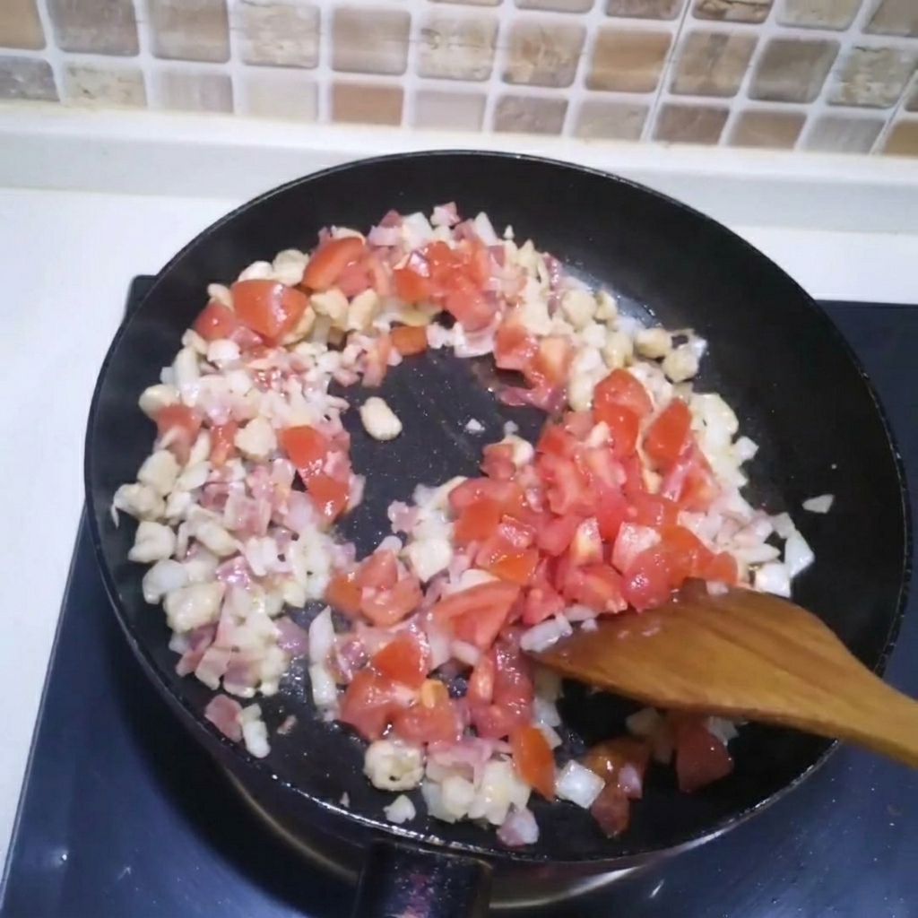 Pomodori a cubetti aggiunti in una padella con carne e cipolle in cottura.