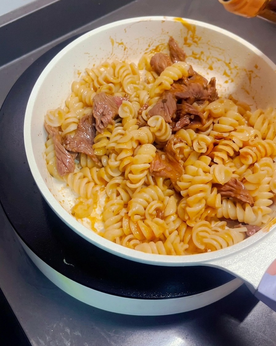 Salsa di soia scura versata sopra la pasta saltata con manzo.