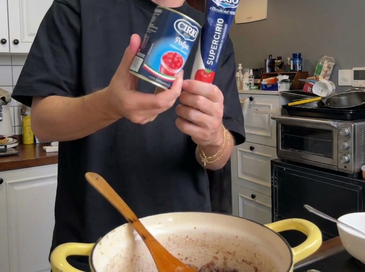 Passata di pomodoro e un tubetto di concentrato sopra la pentola in cottura.