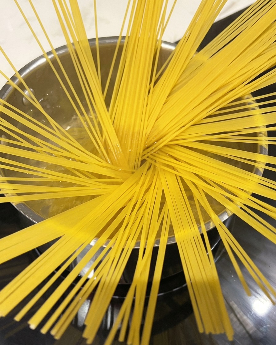 Spaghetti in ebollizione in una pentola capiente con vapore.