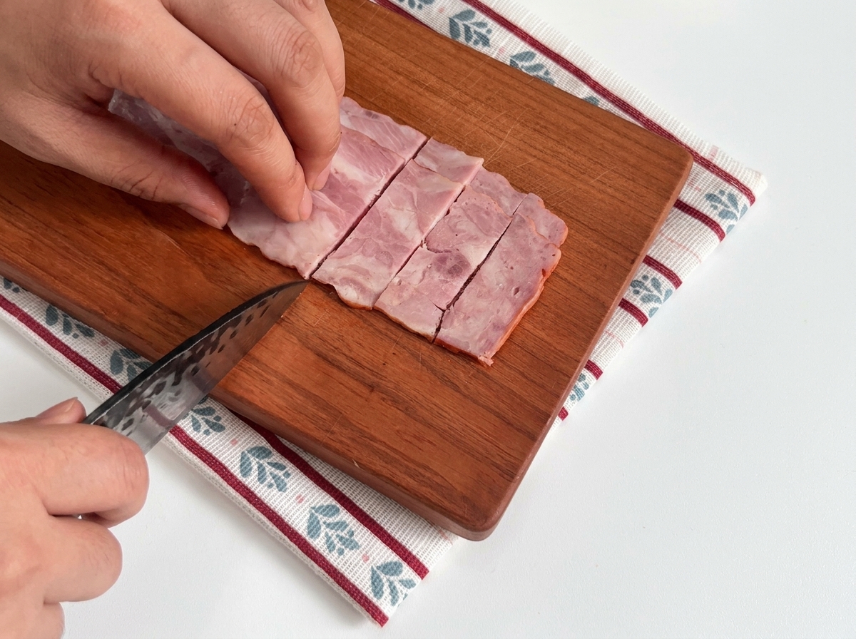 Pezzi di pancetta tagliati su un tagliere di legno.