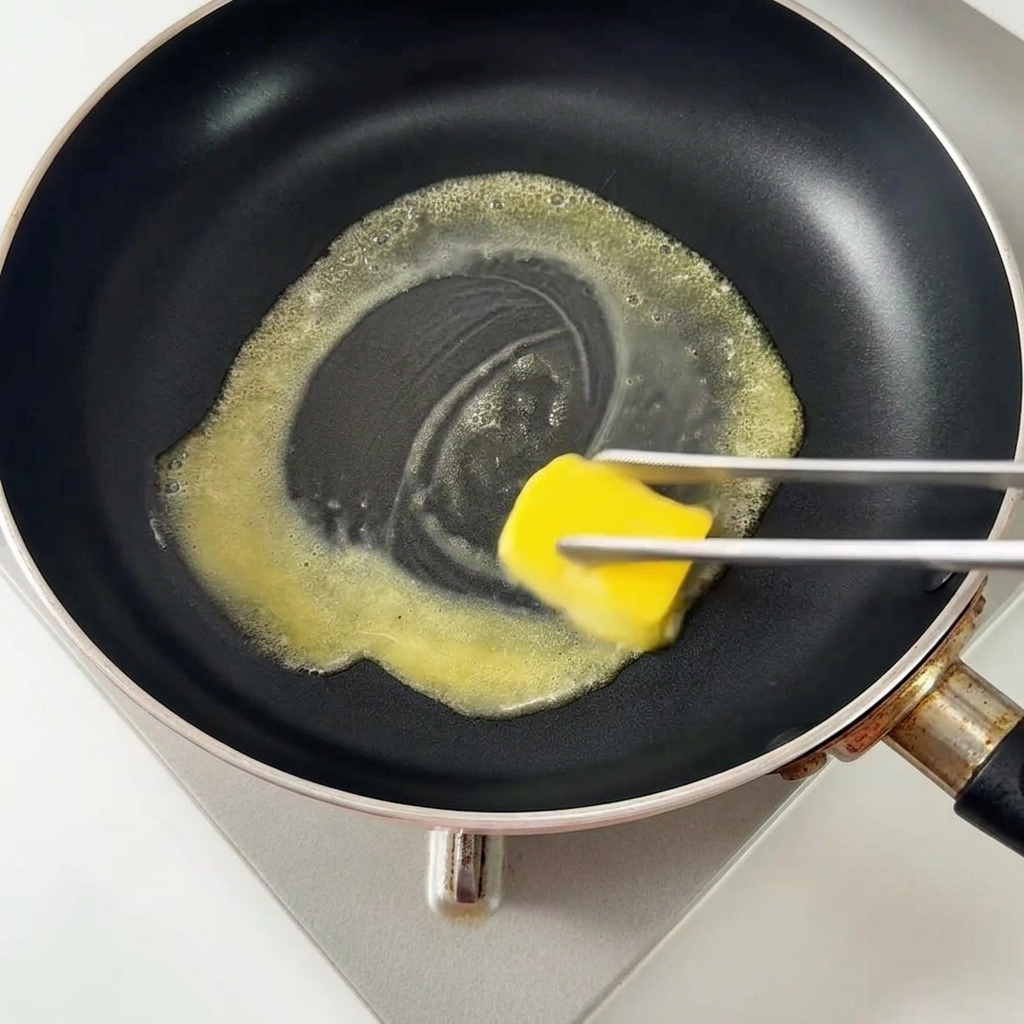 Burro che sfrigola in una padella antiaderente.