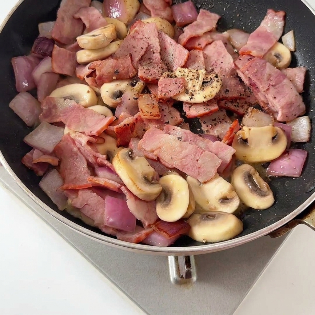 Pepe nero macinato aggiunto sulla pancetta e funghi.