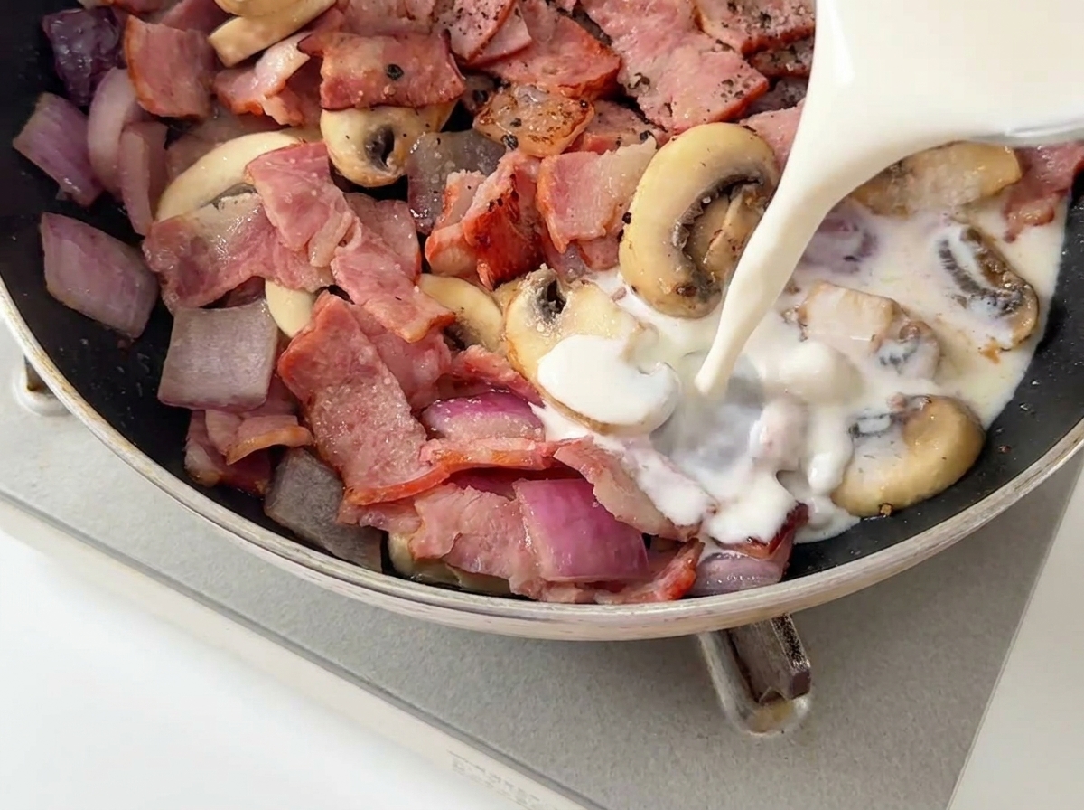 Latte e panna versati nella padella con funghi e pancetta.