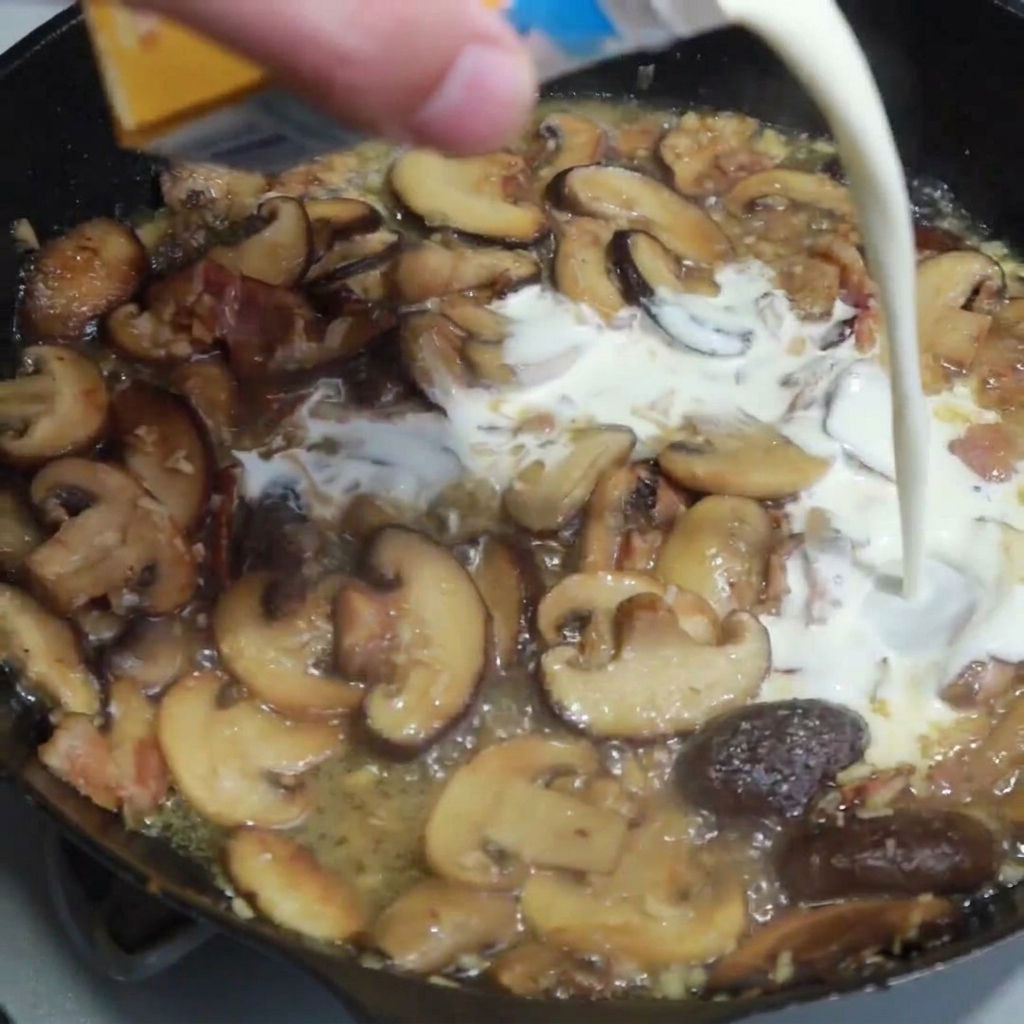 Panna fresca versata in padella con funghi, bacon e aromi dorati.