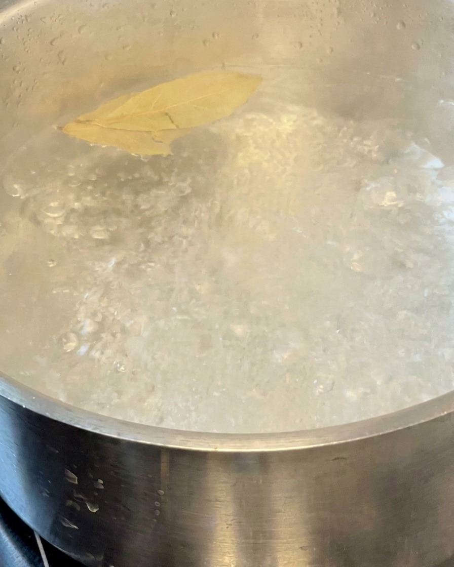 Pasta che cuoce in una pentola dacqua bollente con foglie di alloro.