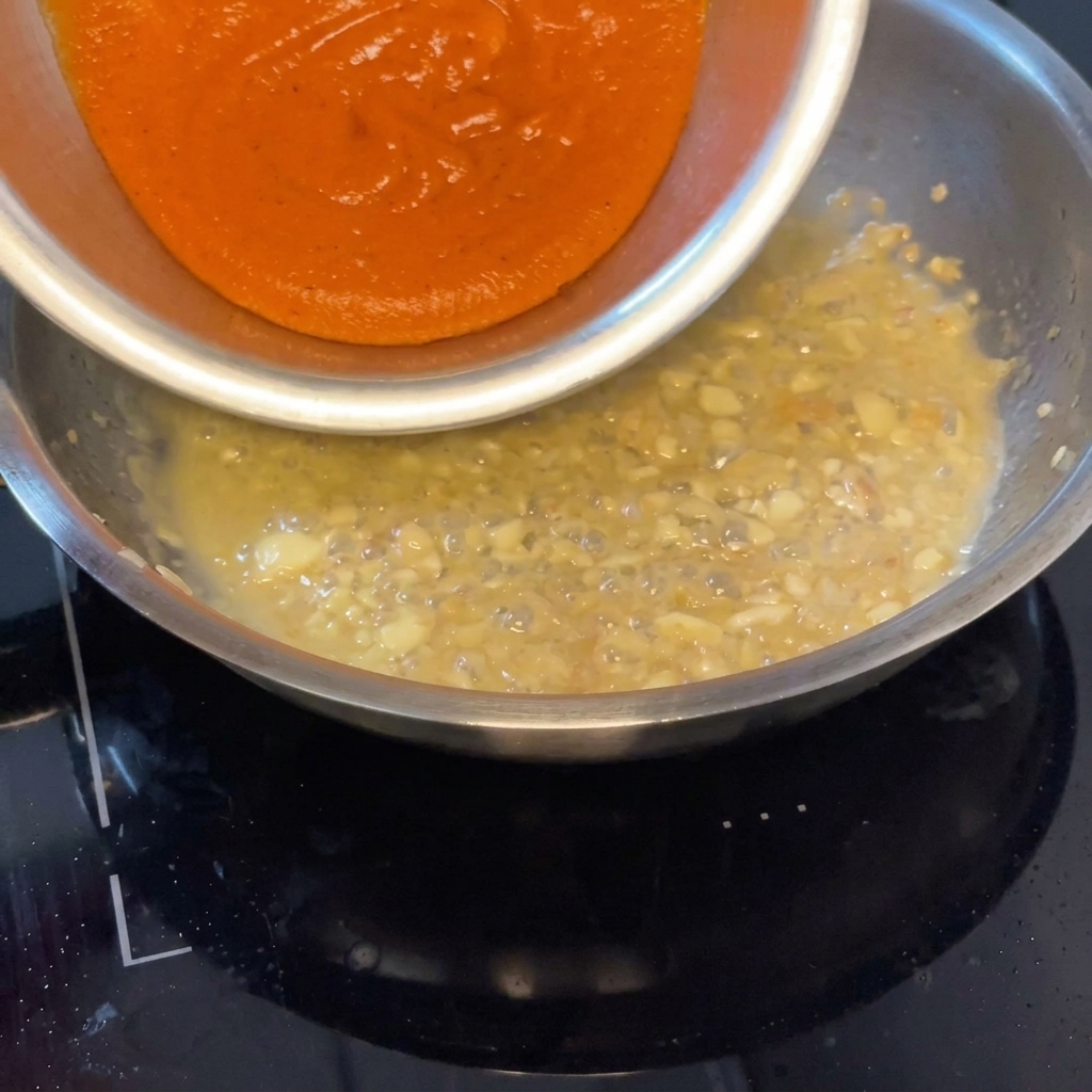 Salsa ai peperoni versata in padella per unirsi al fondo di cottura.