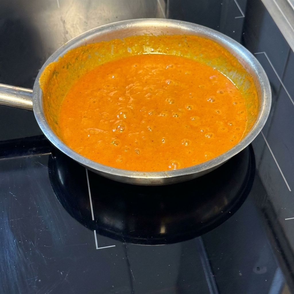 Pasta scolata versata nella padella con la salsa arancione ai peperoni.