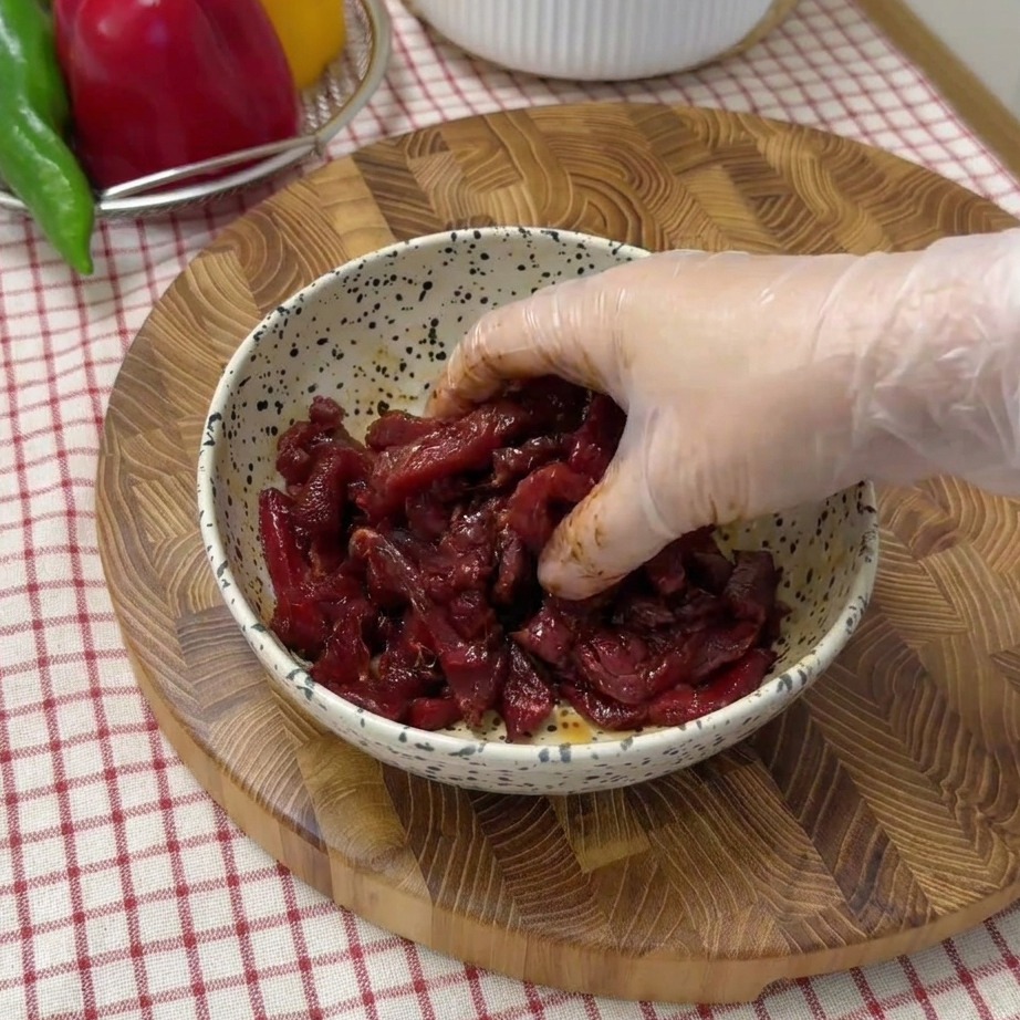 Straccetti di manzo che marinano in una ciotola con salsa di soia e spezie.