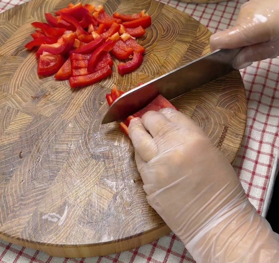Peperoni rossi tagliati a cubetti su un tagliere.