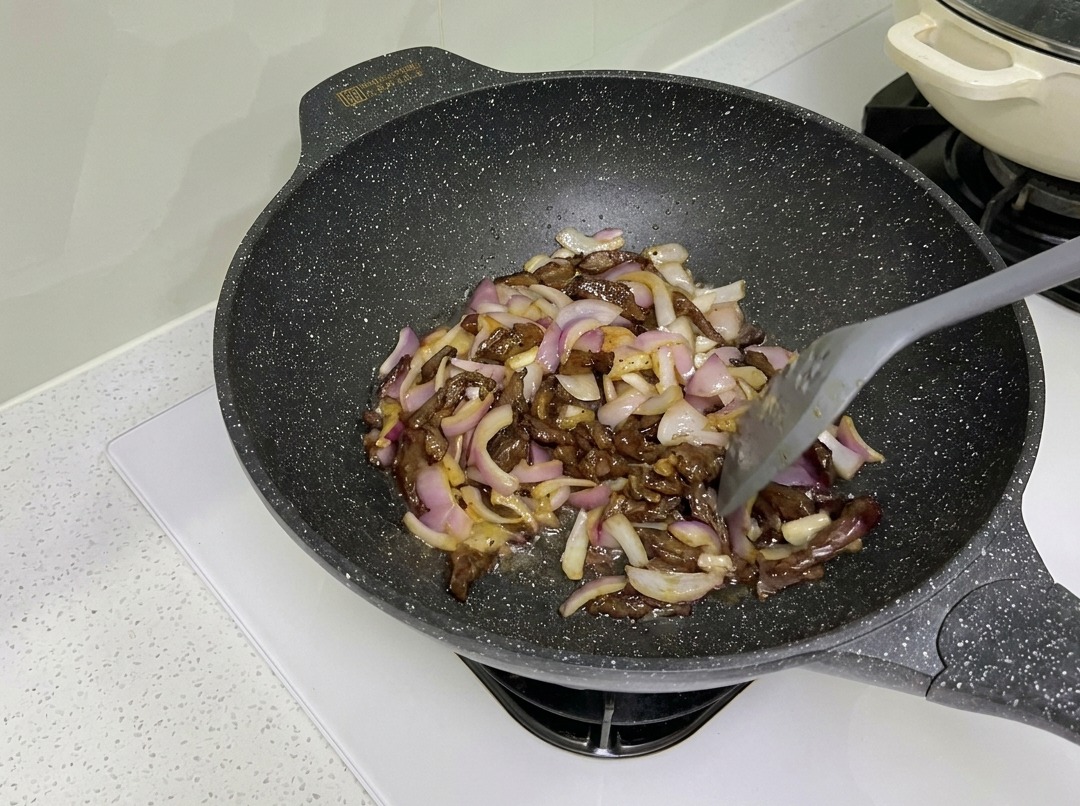 Straccetti di manzo e cipolle rosse saltati insieme nel wok.