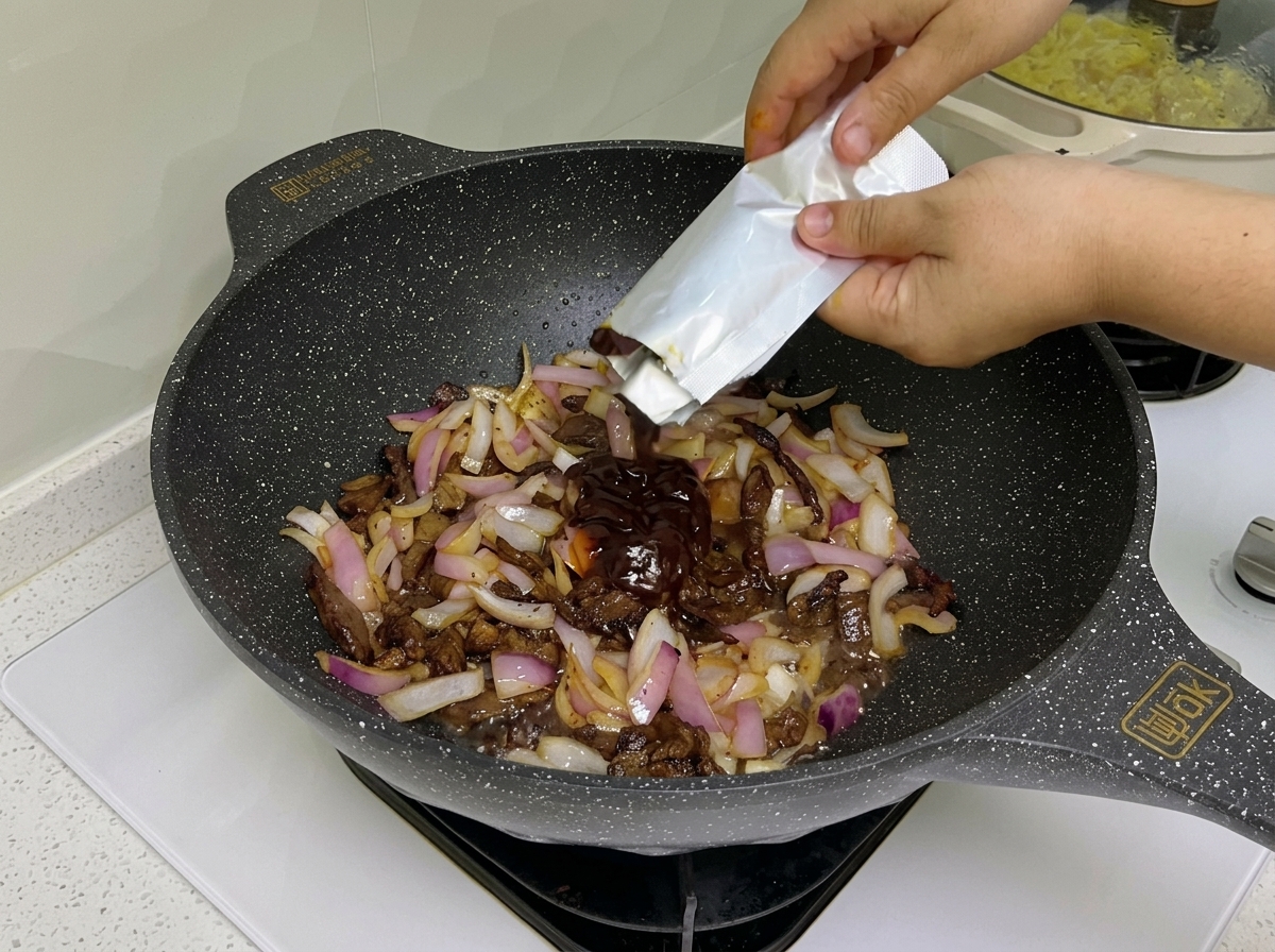 Salsa scura e concentrato di pomodoro mescolati con manzo e cipolla nel wok.