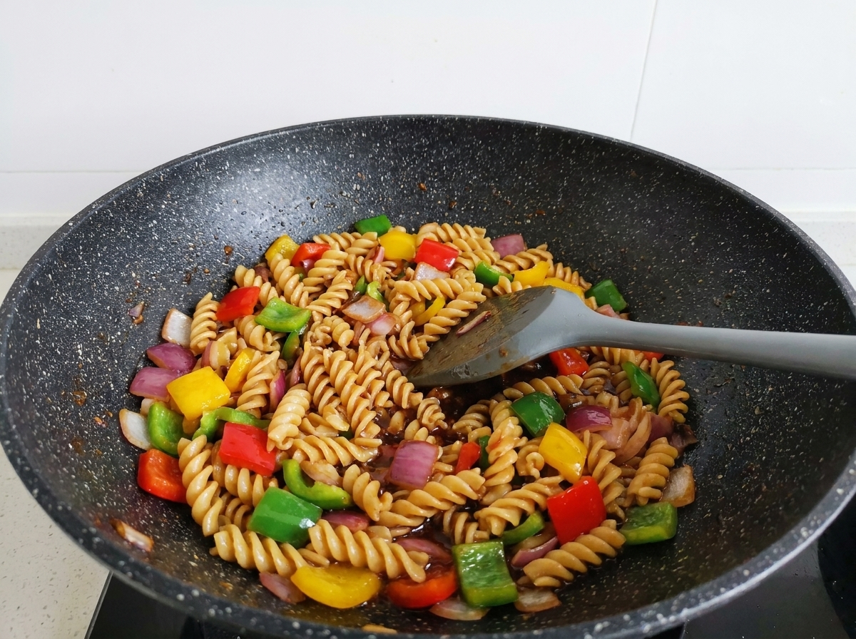 Pasta, manzo e peperoni saltati nel wok, perfettamente ricoperti di salsa scura.