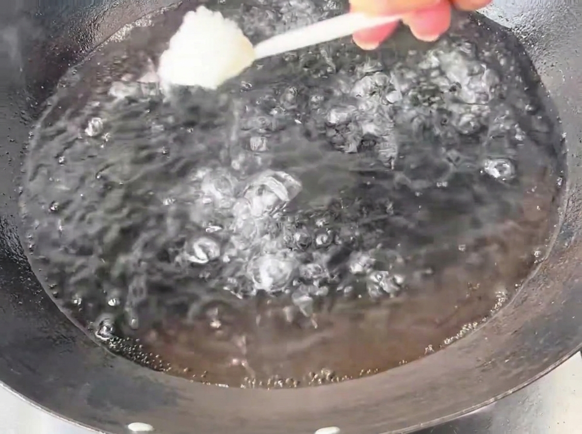 Un cucchiaio di sale versato in un wok capiente pieno di acqua bollente.