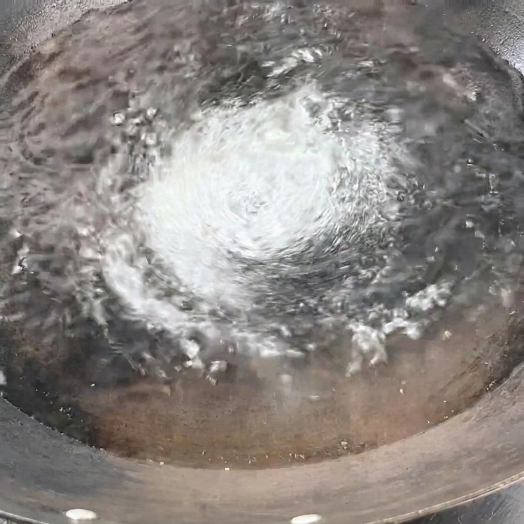 Un fascio di spaghetti secchi immersi nellacqua bollente del wok.
