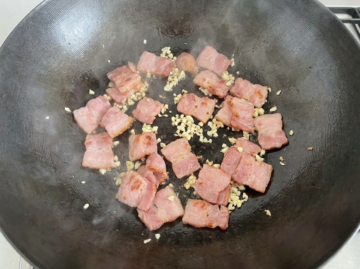 Funghi bianchi affettati versati nel wok insieme alla pancetta e allaglio.
