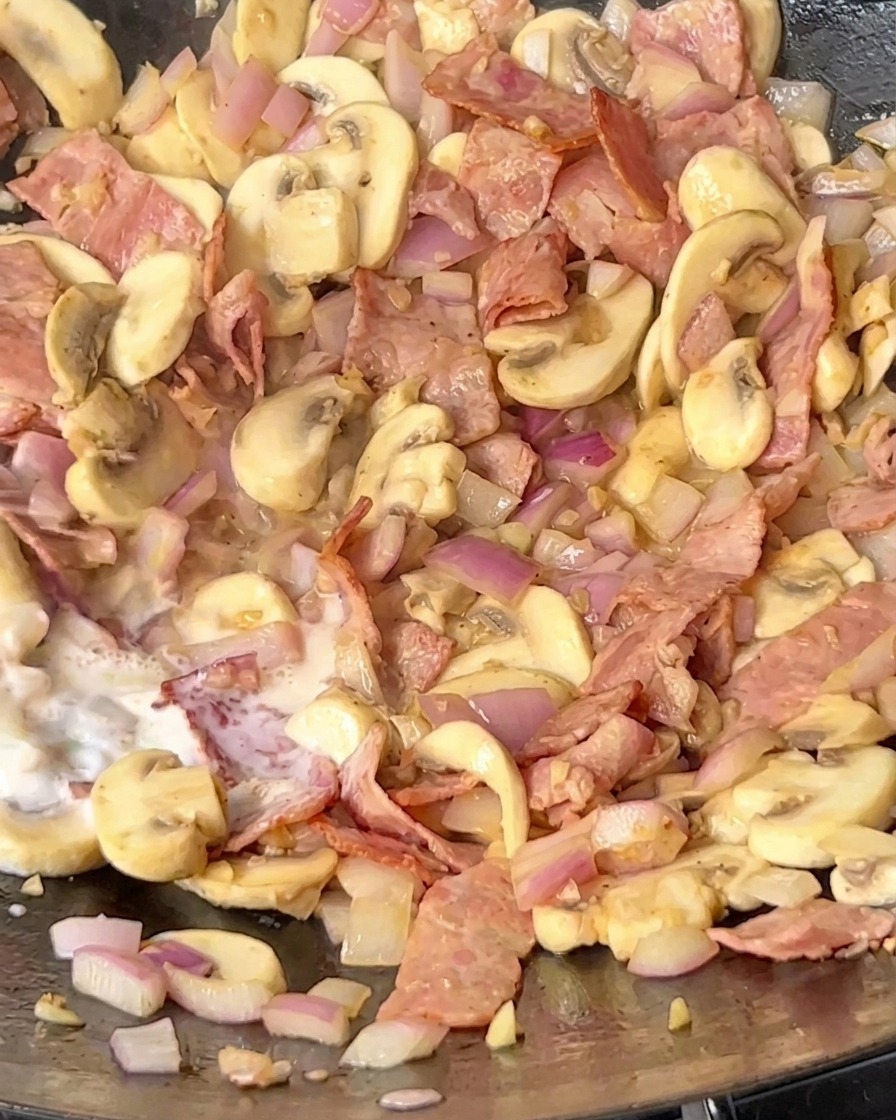 Latte versato nel wok con il soffritto di pancetta, funghi e cipolla.