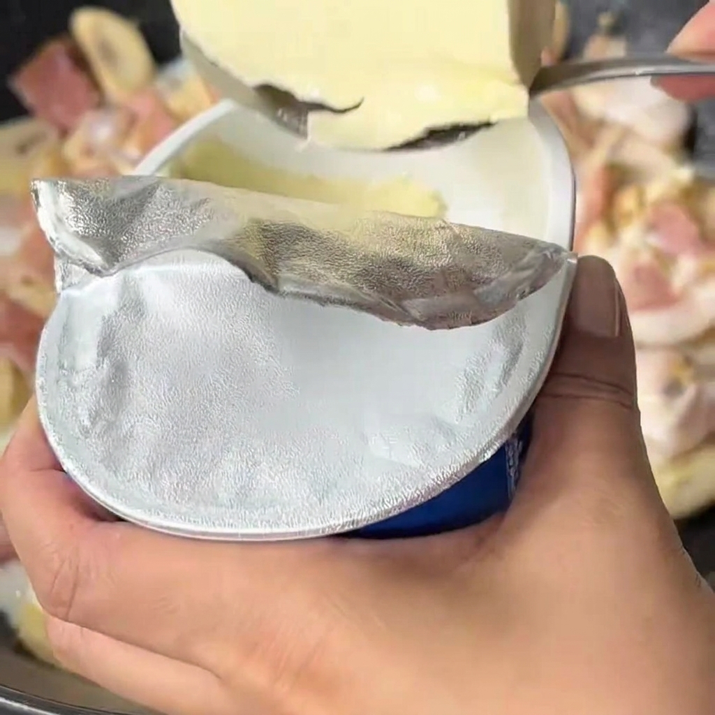 Formaggio spalmabile aggiunto al latte bollente nel wok.