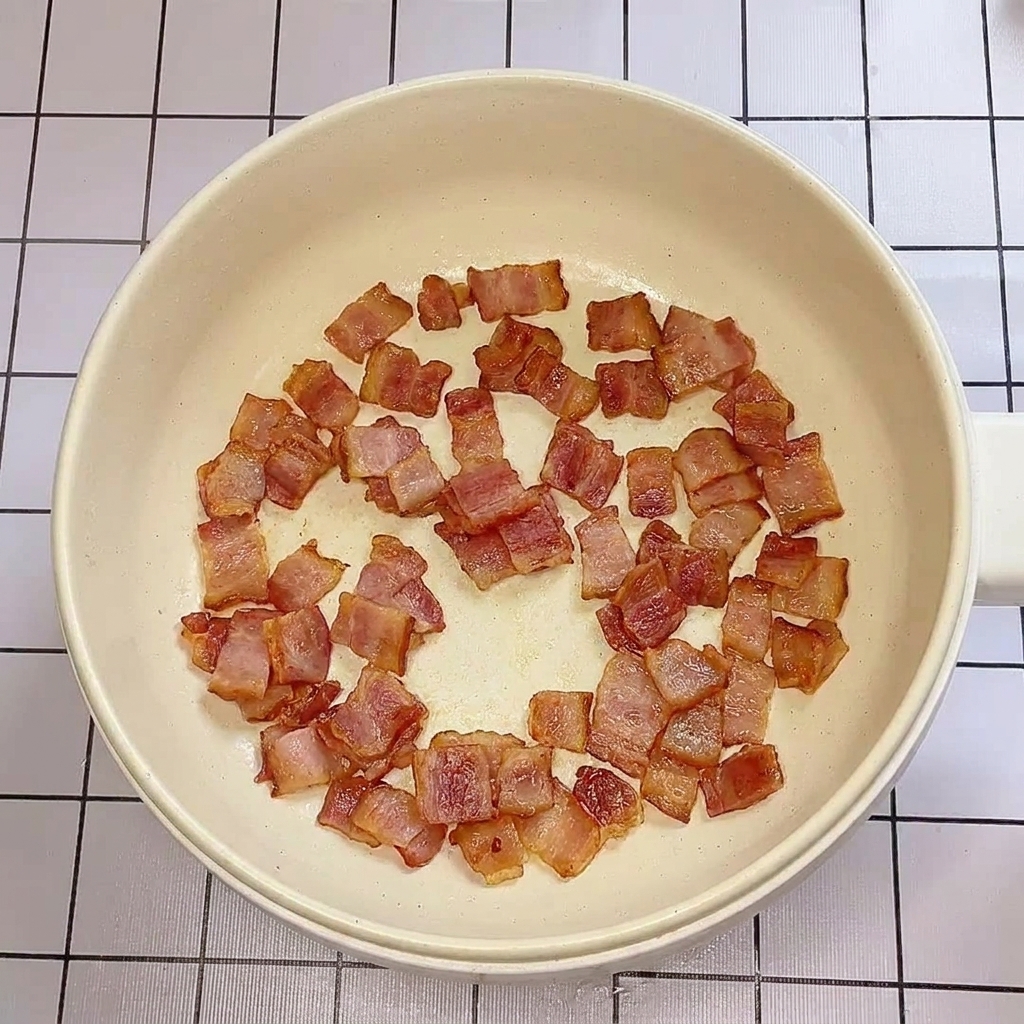 Pezzi di bacon croccanti e dorati che cuociono in una padella.